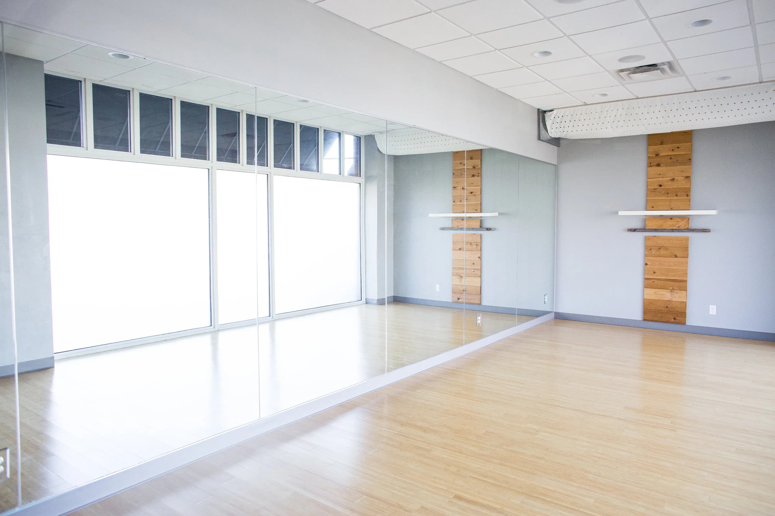 Studio B rental space with a mirrored wall, large windows, and light wood flooring