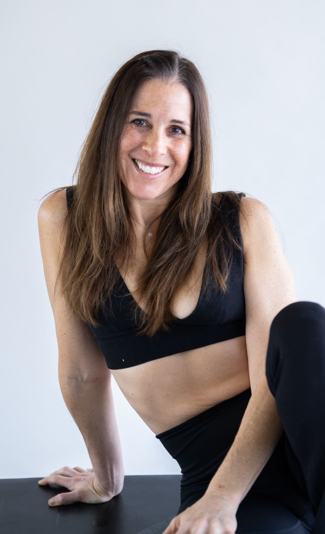 Smiling yoga student portrait seated in a bright studio